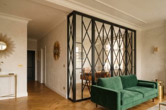 Verrière intérieure Art Déco avec structure métallique noire et motifs géométriques séparant salon et bureau dans une maison moderne